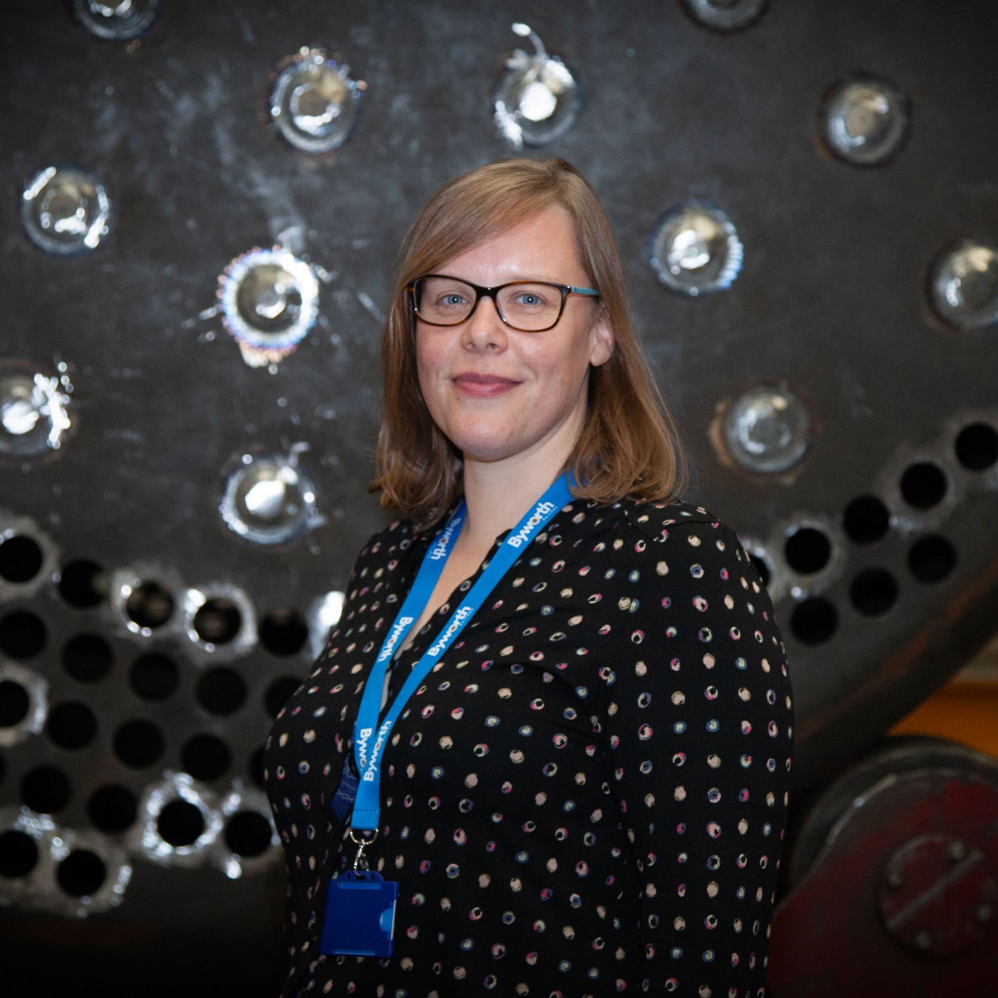 woman smiling for the camera in front of a boiler 